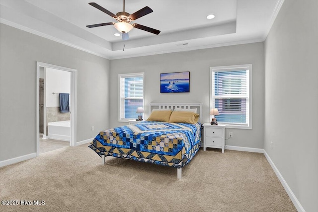 carpeted bedroom with crown molding, a tray ceiling, ceiling fan, and ensuite bathroom