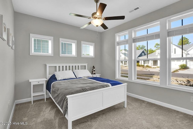 carpeted bedroom featuring multiple windows and ceiling fan