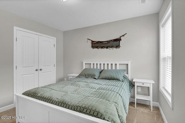 bedroom featuring multiple windows, light colored carpet, and a closet