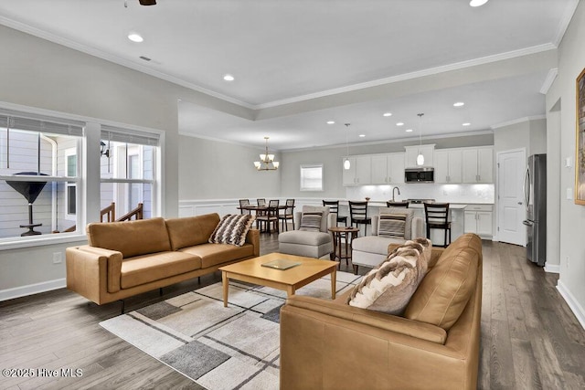 living room featuring an inviting chandelier, ornamental molding, and light wood-type flooring