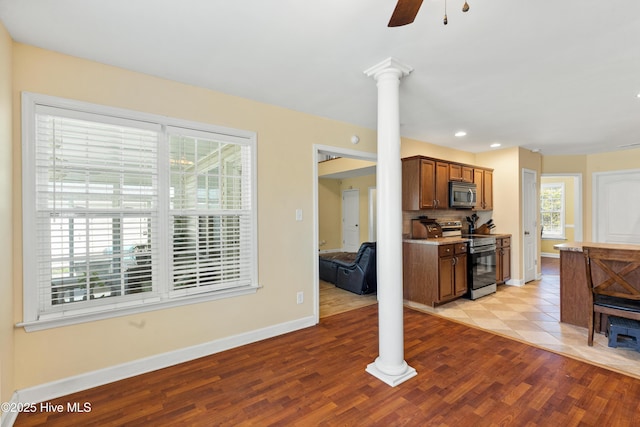 kitchen with ornate columns, light wood-style floors, stainless steel appliances, and decorative backsplash