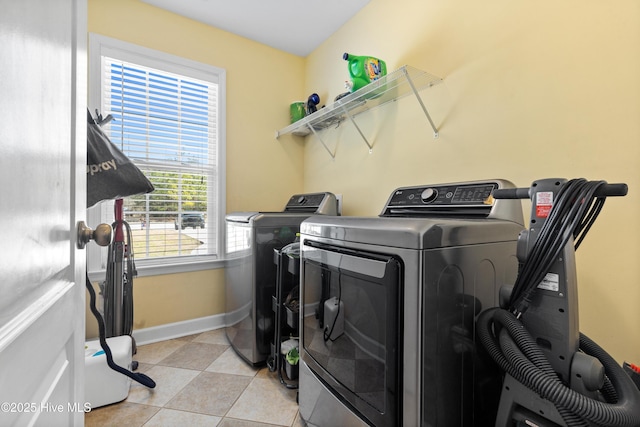 laundry room with light tile patterned floors, laundry area, washing machine and dryer, and baseboards