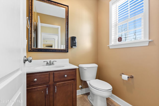 half bath featuring tile patterned flooring, baseboards, vanity, and toilet