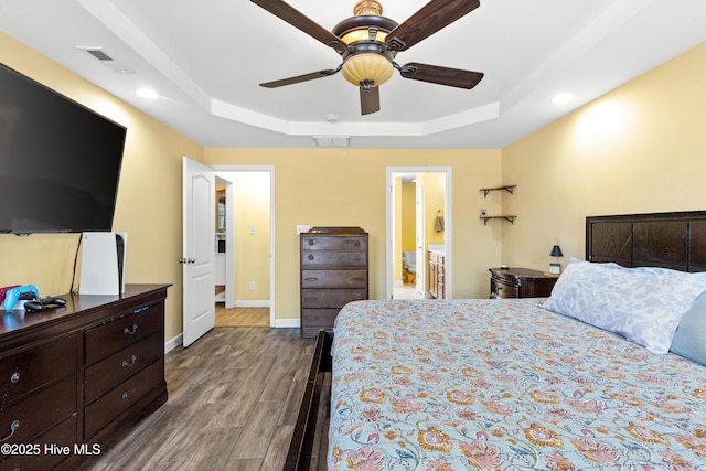 bedroom featuring a raised ceiling, visible vents, baseboards, and wood finished floors