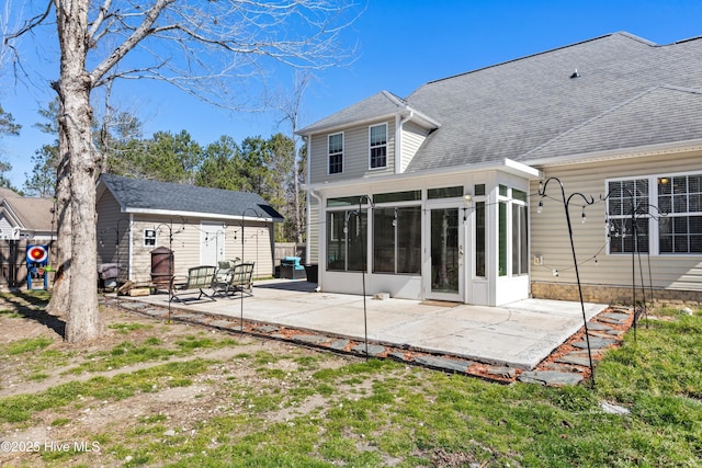 rear view of house featuring a patio area, a shingled roof, a sunroom, and an outdoor structure