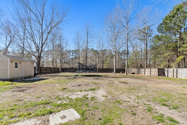 view of yard with a storage shed, a fenced backyard, a trampoline, and an outdoor structure