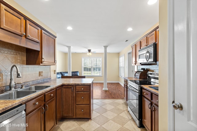 kitchen with decorative columns, a ceiling fan, a peninsula, stainless steel appliances, and a sink