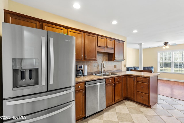 kitchen featuring stainless steel appliances, tasteful backsplash, a sink, a peninsula, and ornate columns