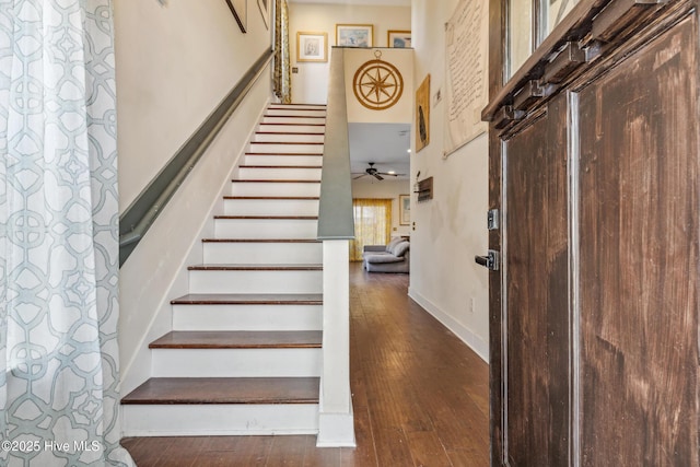 stairway featuring hardwood / wood-style floors, a towering ceiling, and ceiling fan