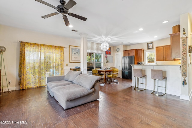 living room featuring wood-type flooring, decorative columns, and ceiling fan