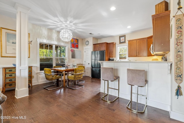 kitchen featuring a healthy amount of sunlight, black refrigerator, dark hardwood / wood-style flooring, and kitchen peninsula