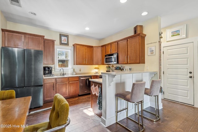 kitchen featuring stainless steel appliances, sink, wood-type flooring, and a breakfast bar area