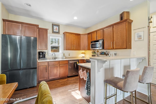 kitchen featuring hardwood / wood-style floors, sink, a breakfast bar area, kitchen peninsula, and stainless steel appliances