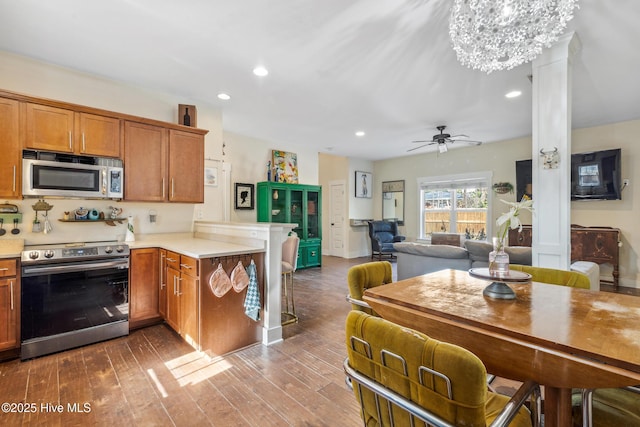 kitchen featuring appliances with stainless steel finishes, a breakfast bar, hardwood / wood-style floors, and kitchen peninsula