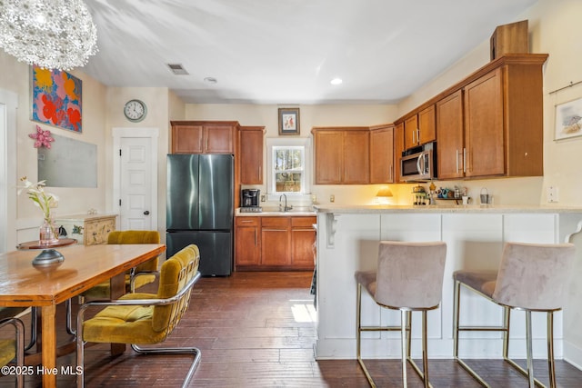 kitchen with appliances with stainless steel finishes, sink, dark hardwood / wood-style flooring, a kitchen breakfast bar, and kitchen peninsula