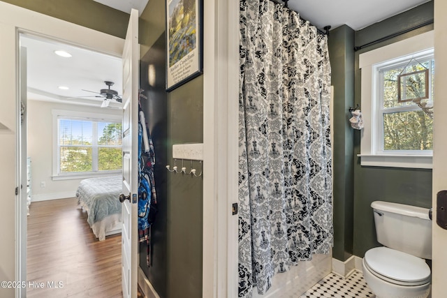 bathroom featuring wood-type flooring, toilet, a shower with shower curtain, and a wealth of natural light