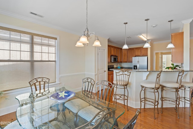 dining room featuring ornamental molding, light hardwood / wood-style floors, and a healthy amount of sunlight