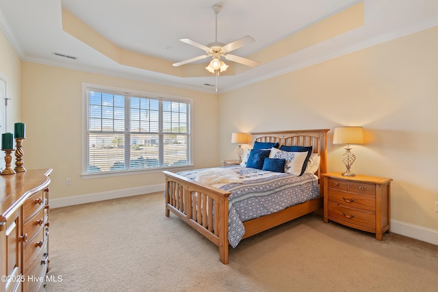 bedroom featuring ornamental molding, light carpet, ceiling fan, and a tray ceiling