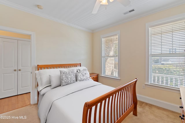 bedroom with ceiling fan, ornamental molding, light carpet, and multiple windows