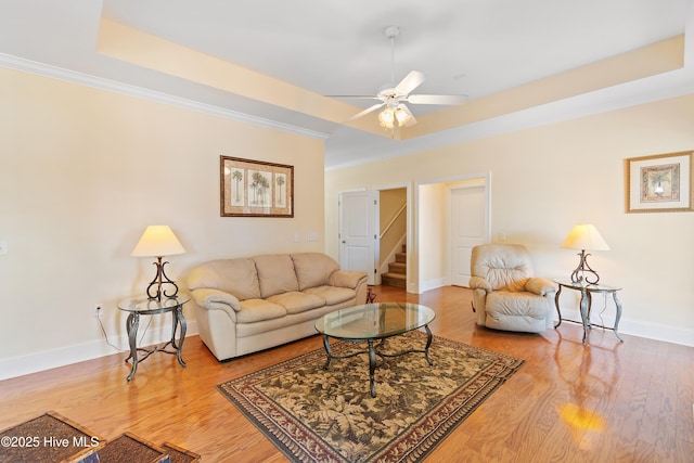 living room featuring crown molding, a tray ceiling, ceiling fan, and hardwood / wood-style flooring