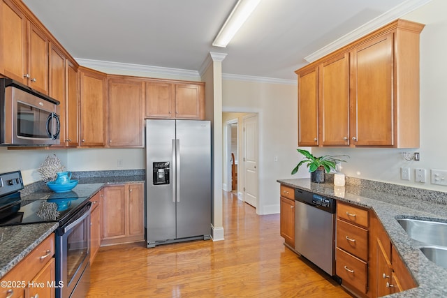 kitchen with sink, crown molding, light hardwood / wood-style flooring, appliances with stainless steel finishes, and dark stone counters