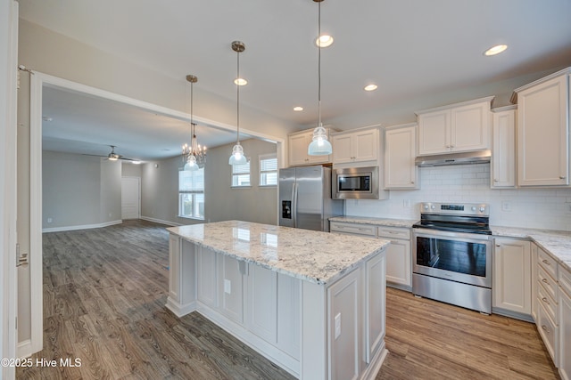 kitchen featuring pendant lighting, light stone countertops, white cabinets, and appliances with stainless steel finishes