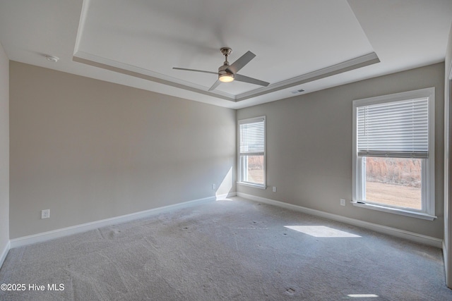 carpeted empty room featuring a raised ceiling and ceiling fan