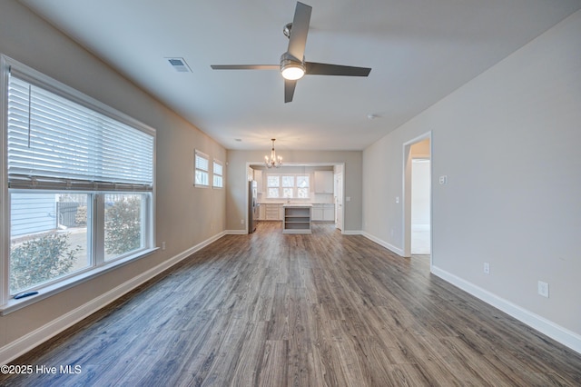 unfurnished living room with dark hardwood / wood-style floors and ceiling fan with notable chandelier