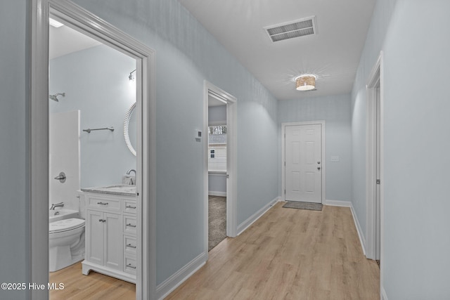 hallway with sink and light wood-type flooring