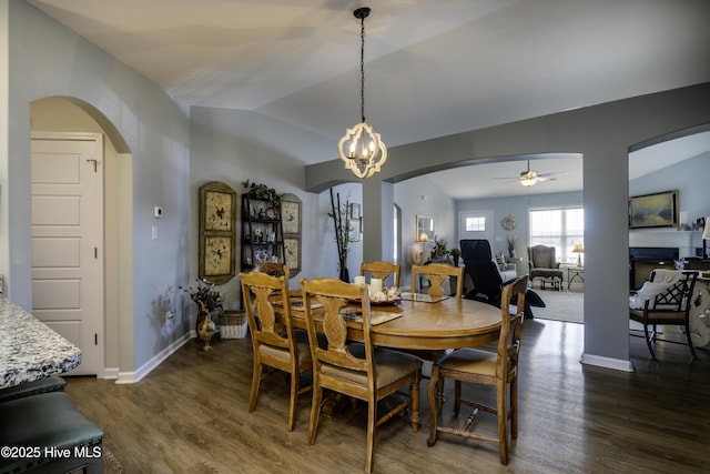 dining space featuring lofted ceiling, dark hardwood / wood-style floors, and ceiling fan with notable chandelier