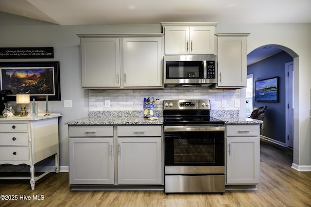 kitchen featuring light stone counters, appliances with stainless steel finishes, and decorative backsplash