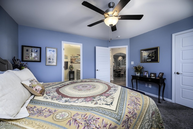 bedroom with ceiling fan, connected bathroom, and dark carpet