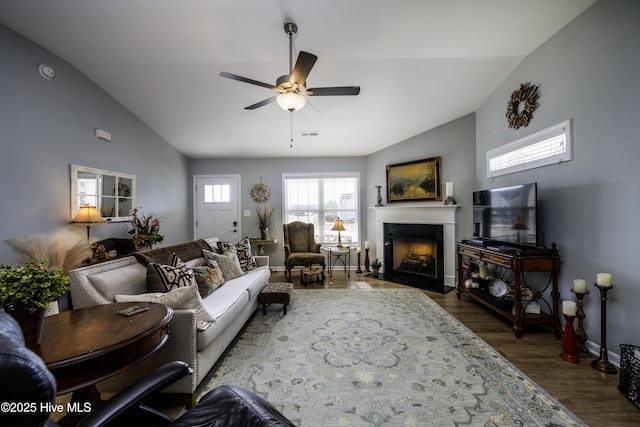 living room with dark wood-type flooring, ceiling fan, and vaulted ceiling