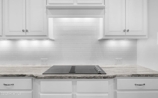 kitchen with black electric stovetop, light stone countertops, and white cabinets