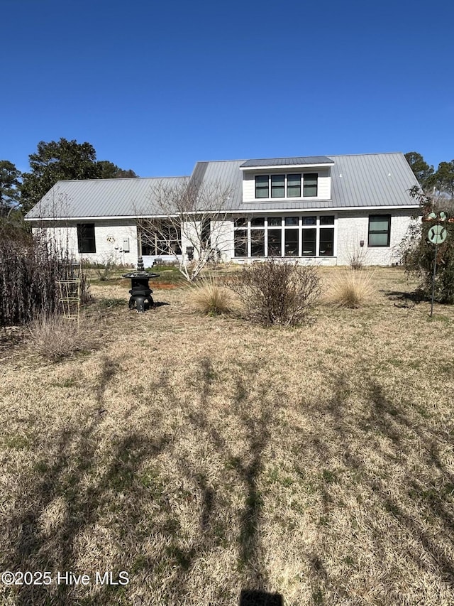 back of property with metal roof and a yard