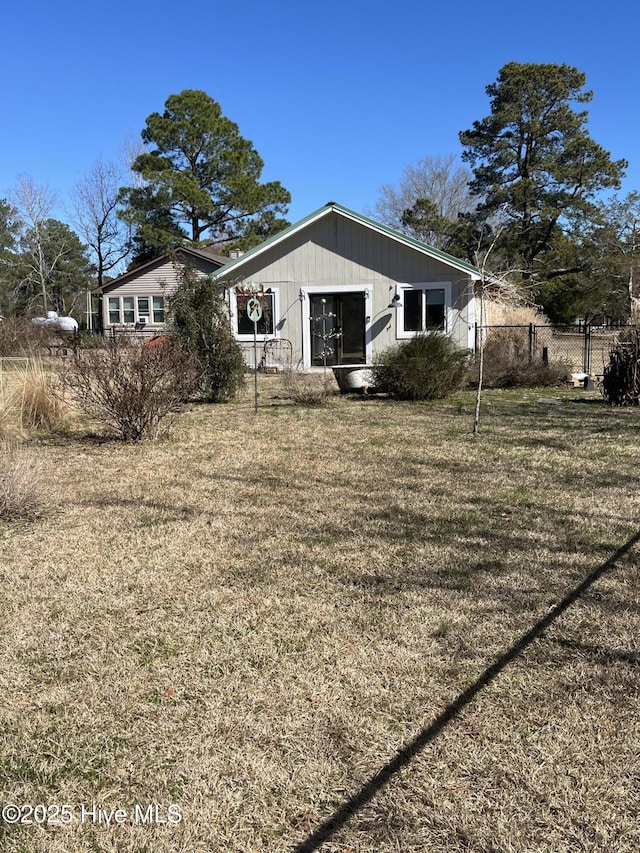 rear view of property featuring fence and a yard