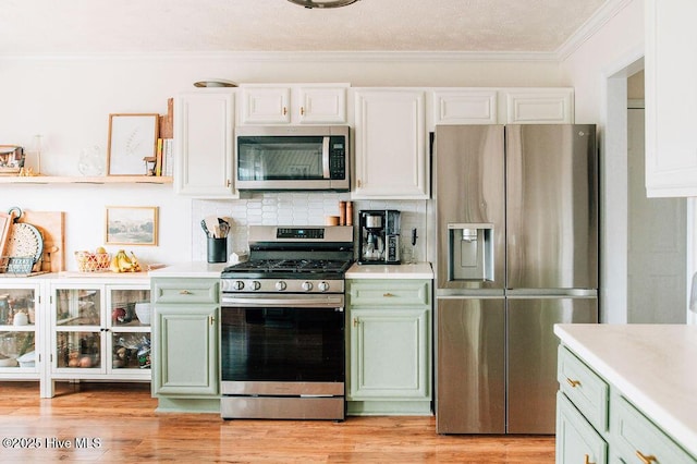 kitchen with ornamental molding, appliances with stainless steel finishes, and green cabinets