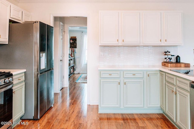 kitchen with backsplash, light hardwood / wood-style flooring, white cabinets, and appliances with stainless steel finishes