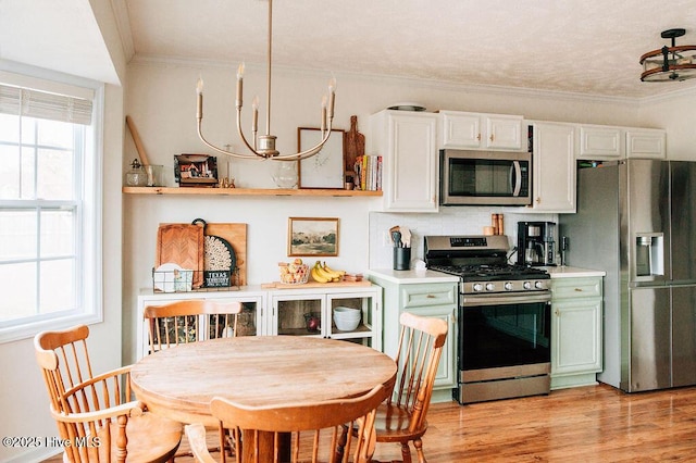 kitchen featuring appliances with stainless steel finishes, backsplash, ornamental molding, white cabinets, and light wood-type flooring