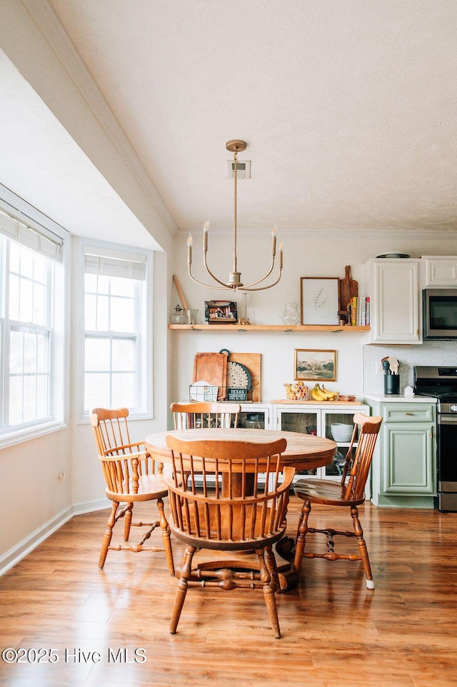 dining space with ornamental molding, light hardwood / wood-style floors, and a textured ceiling