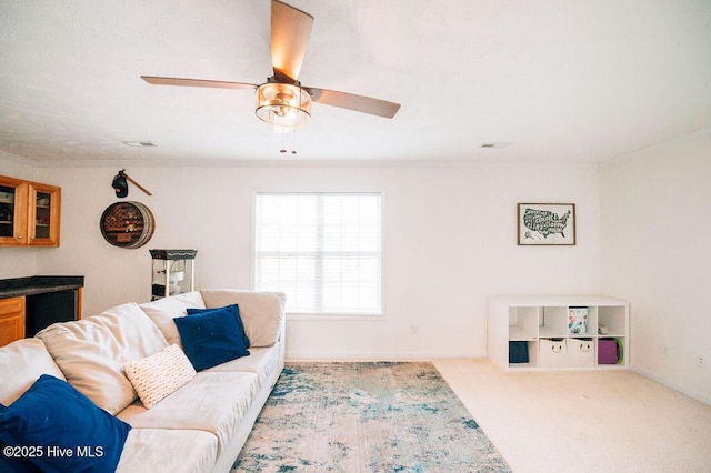 living room with ornamental molding, light colored carpet, and ceiling fan