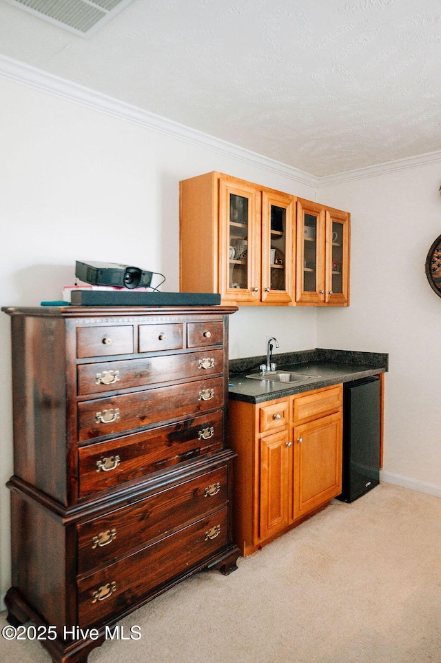 kitchen featuring fridge, light colored carpet, ornamental molding, and sink