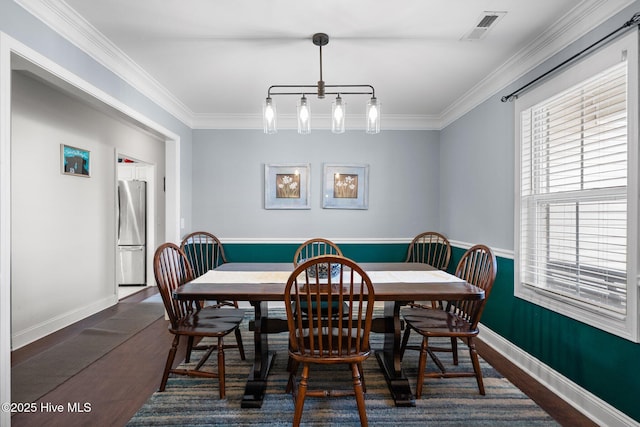 dining space featuring ornamental molding, a notable chandelier, and dark hardwood / wood-style flooring