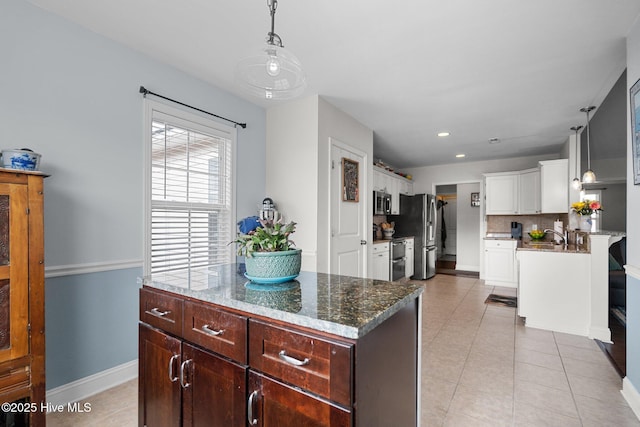 kitchen with white cabinetry, hanging light fixtures, light tile patterned floors, a kitchen island, and stainless steel appliances