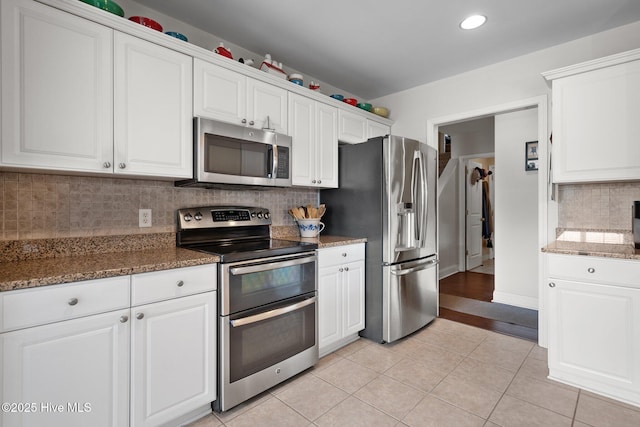 kitchen featuring dark stone countertops, stainless steel appliances, and white cabinets