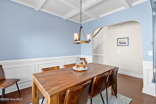 dining area featuring ornamental molding, coffered ceiling, a notable chandelier, dark wood-type flooring, and beam ceiling