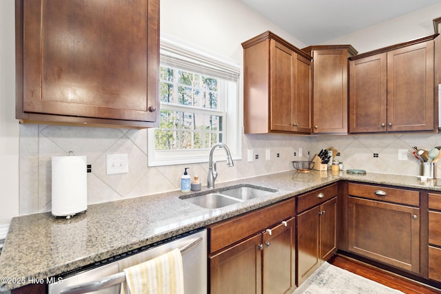 kitchen with tasteful backsplash, sink, light stone countertops, and dishwasher