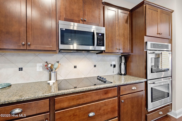 kitchen with tasteful backsplash, light stone countertops, and appliances with stainless steel finishes