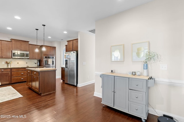 kitchen with a kitchen island, decorative backsplash, hanging light fixtures, stainless steel appliances, and dark wood-type flooring