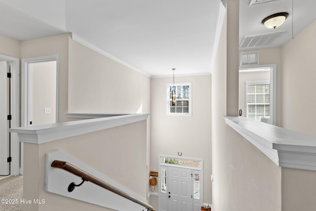 stairs with ornamental molding, plenty of natural light, and a chandelier